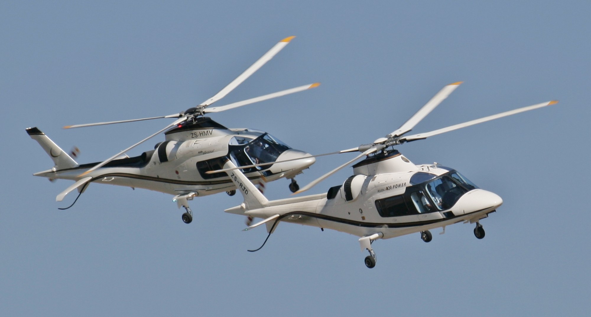 Two Agusta A109 helicopters in flight